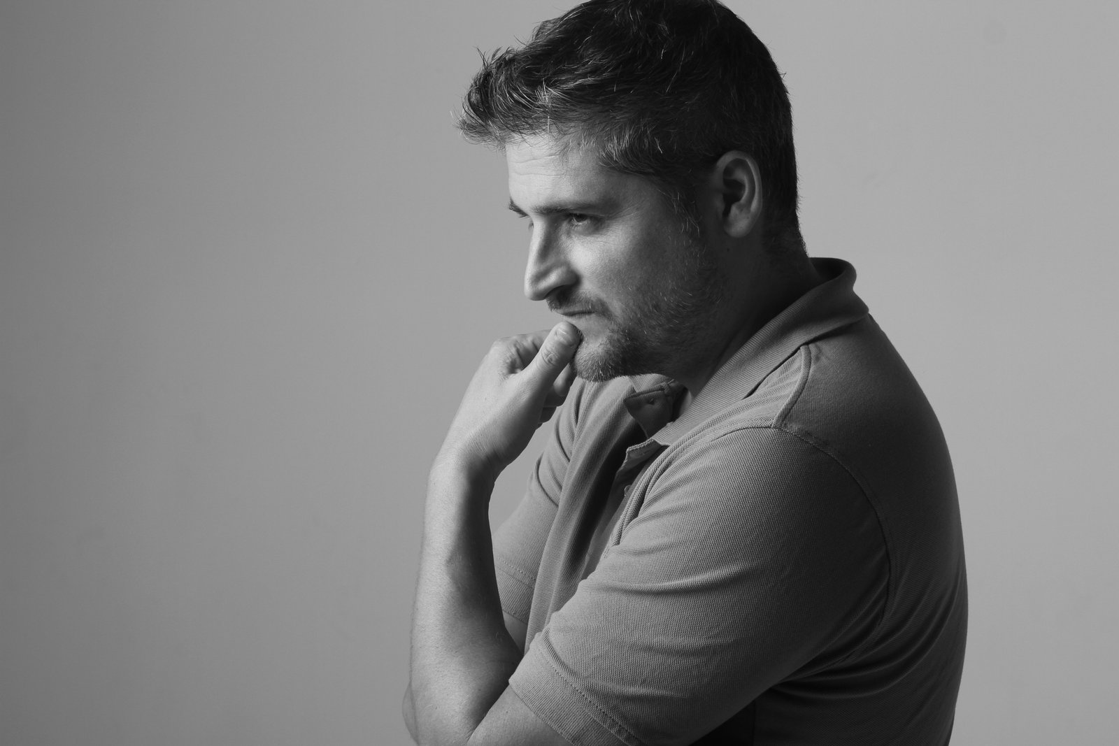 Black and white profile of a man with hand on chin, looking thoughtful, against a plain background.